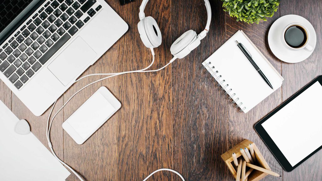 desk with headphones notepad and laptop